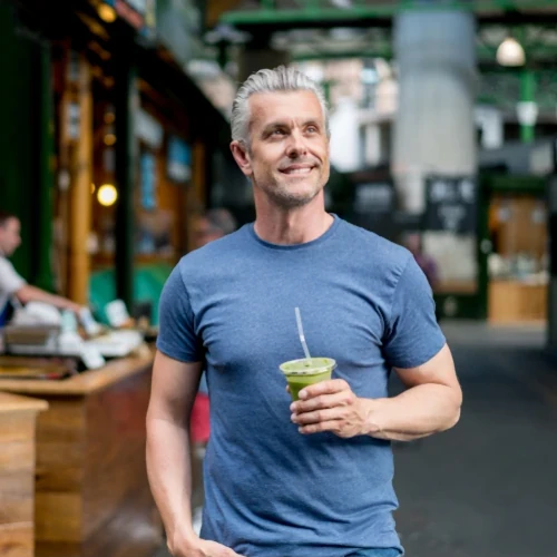 Guy with grey hair enjoying a smoothie made with Project Biotech's healthy greens powder